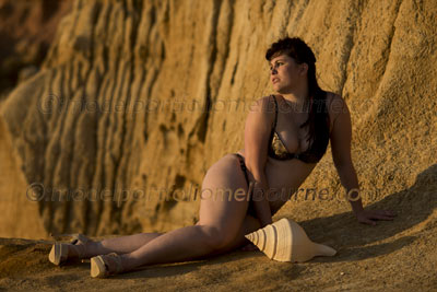 lingerie plus-sized model lies on sand with conch shell